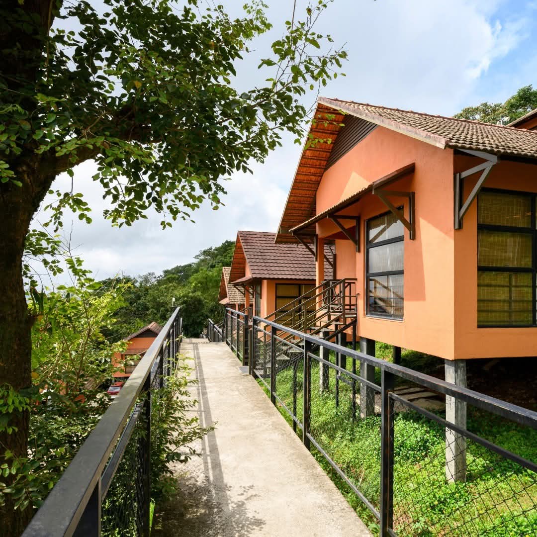 Stilted terracotta cottages along the valley-edge walkway at Heyday Thazhvaram, Panchalimedu, Idukki, Kerala