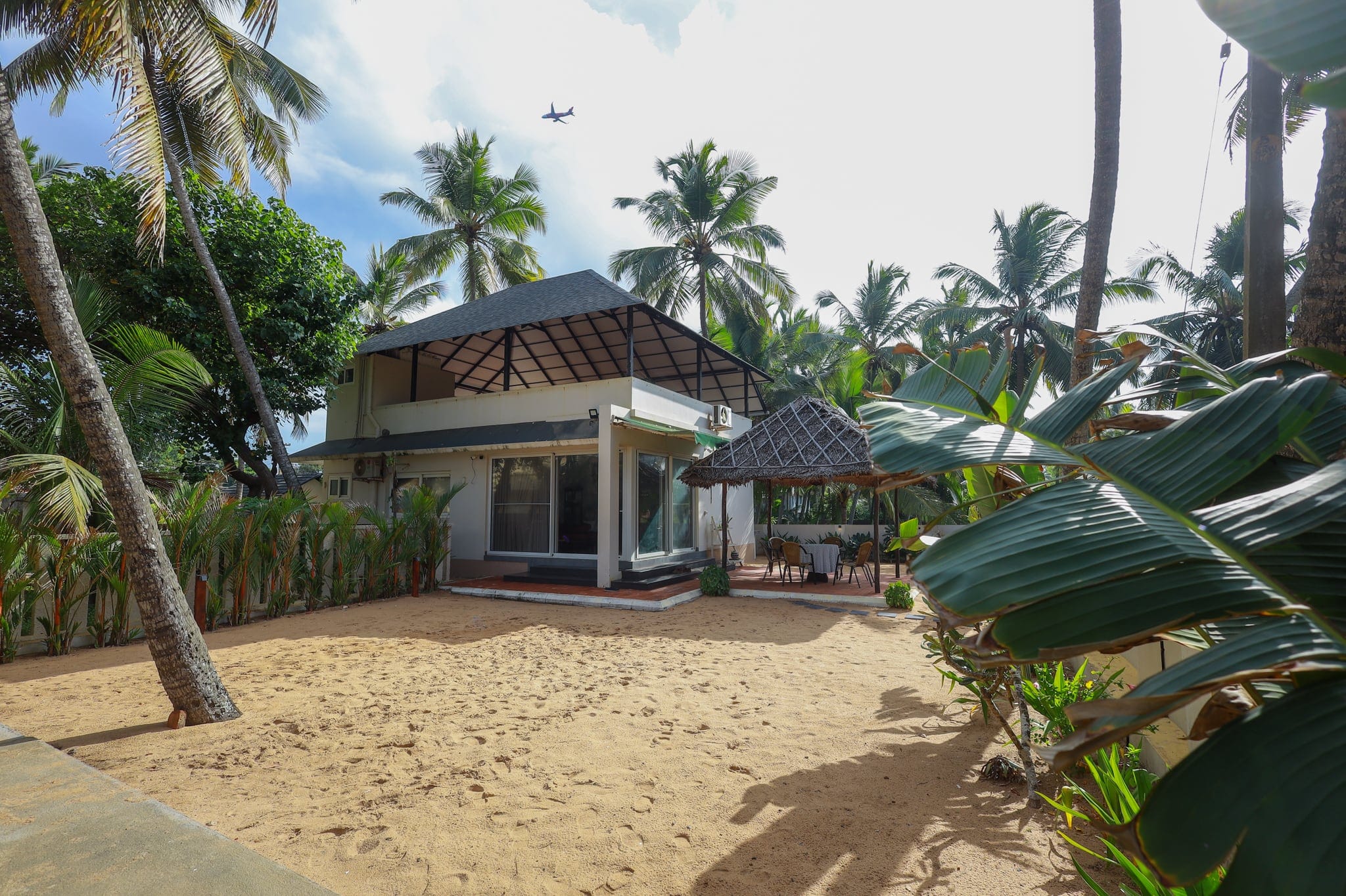 Whitewashed garden cottage among coconut palms at Heyday by the Sea, Veli, Thiruvananthapuram, Kerala